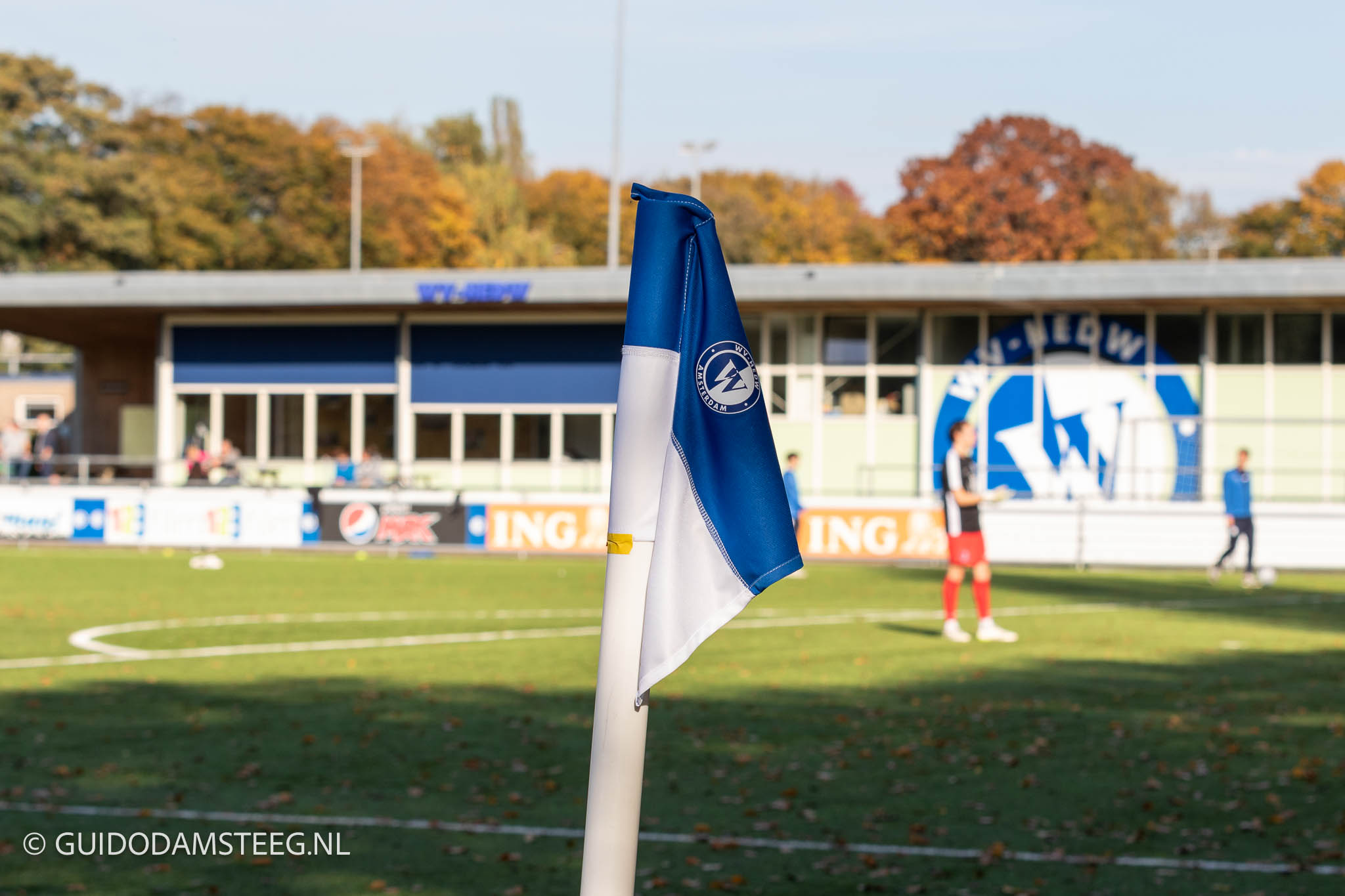 Cornervlag WV-HEDW met in de achtergrond het clubhuis met logo.