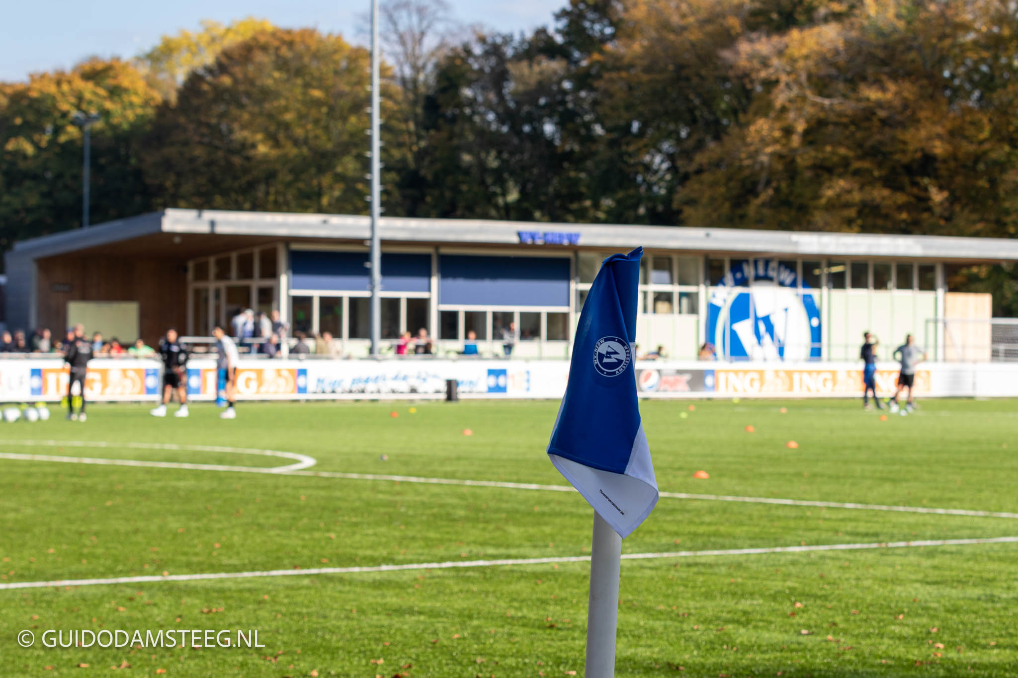 Cornervlag WV-HEDW met in de achtergrond het clubhuis met logo.